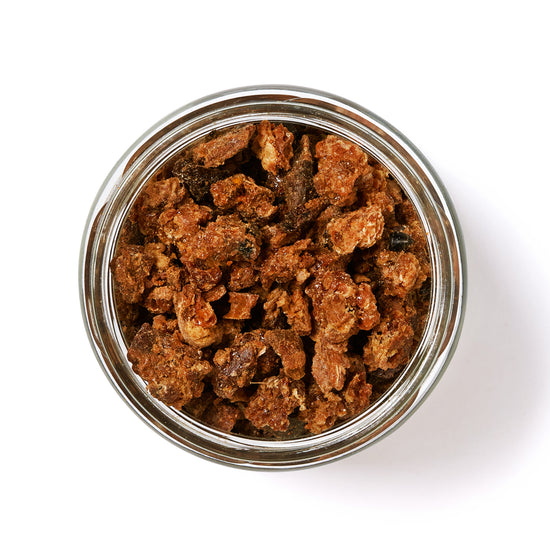 Open glass jar of raw propolis pieces, top view