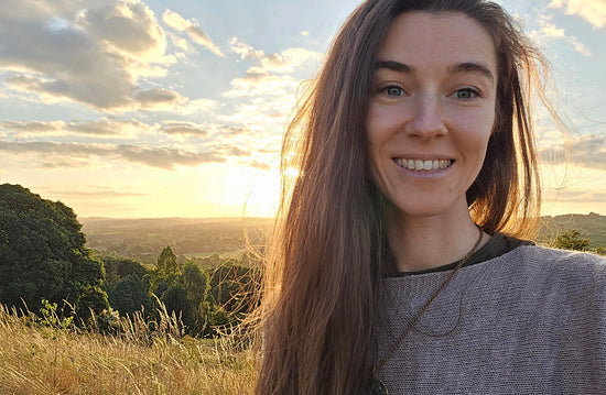Liga smiling outdoors with the low sun over green countryside