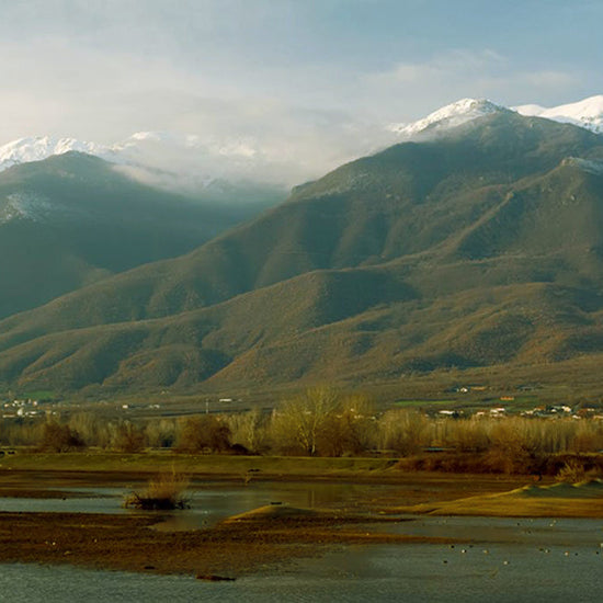 Snow-capped Belles mountains above a lakeside valley with villages