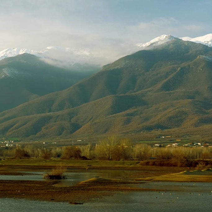 Snow-capped Belles mountains above a lakeside valley with villages