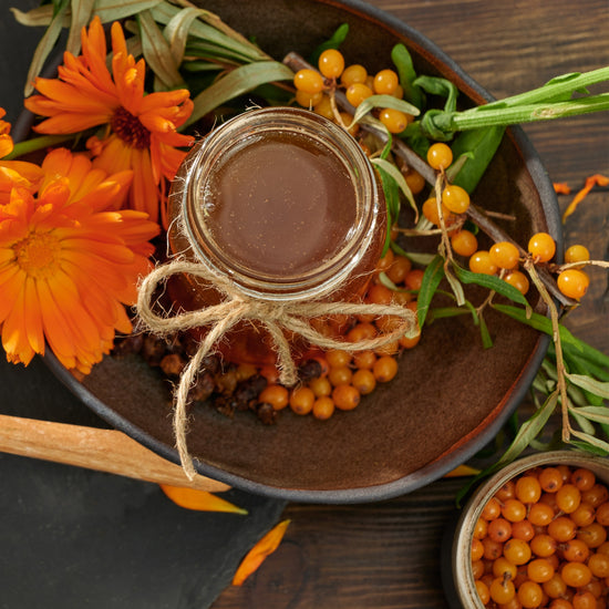 Twine-tied jar of honey with sea buckthorn berries and calendula flowers